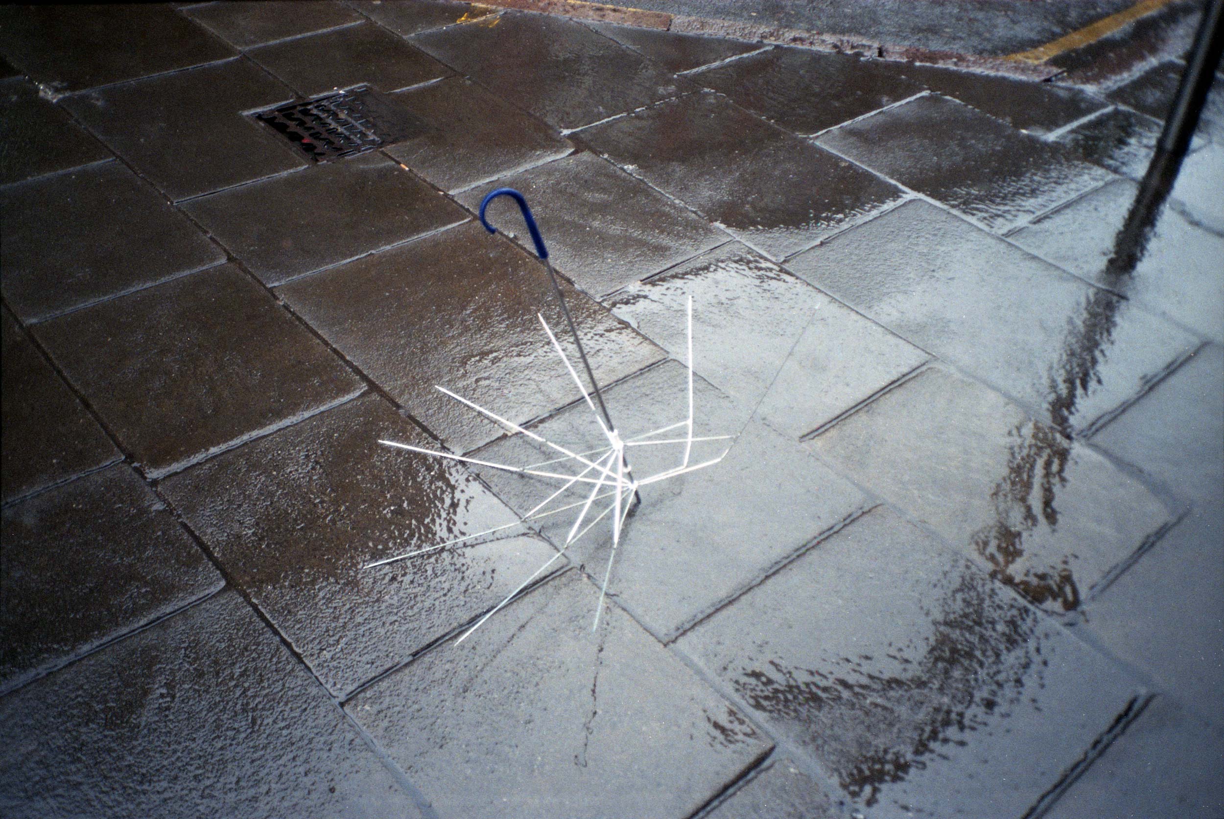 Kaputter Regenschirm auf nasser Straße.