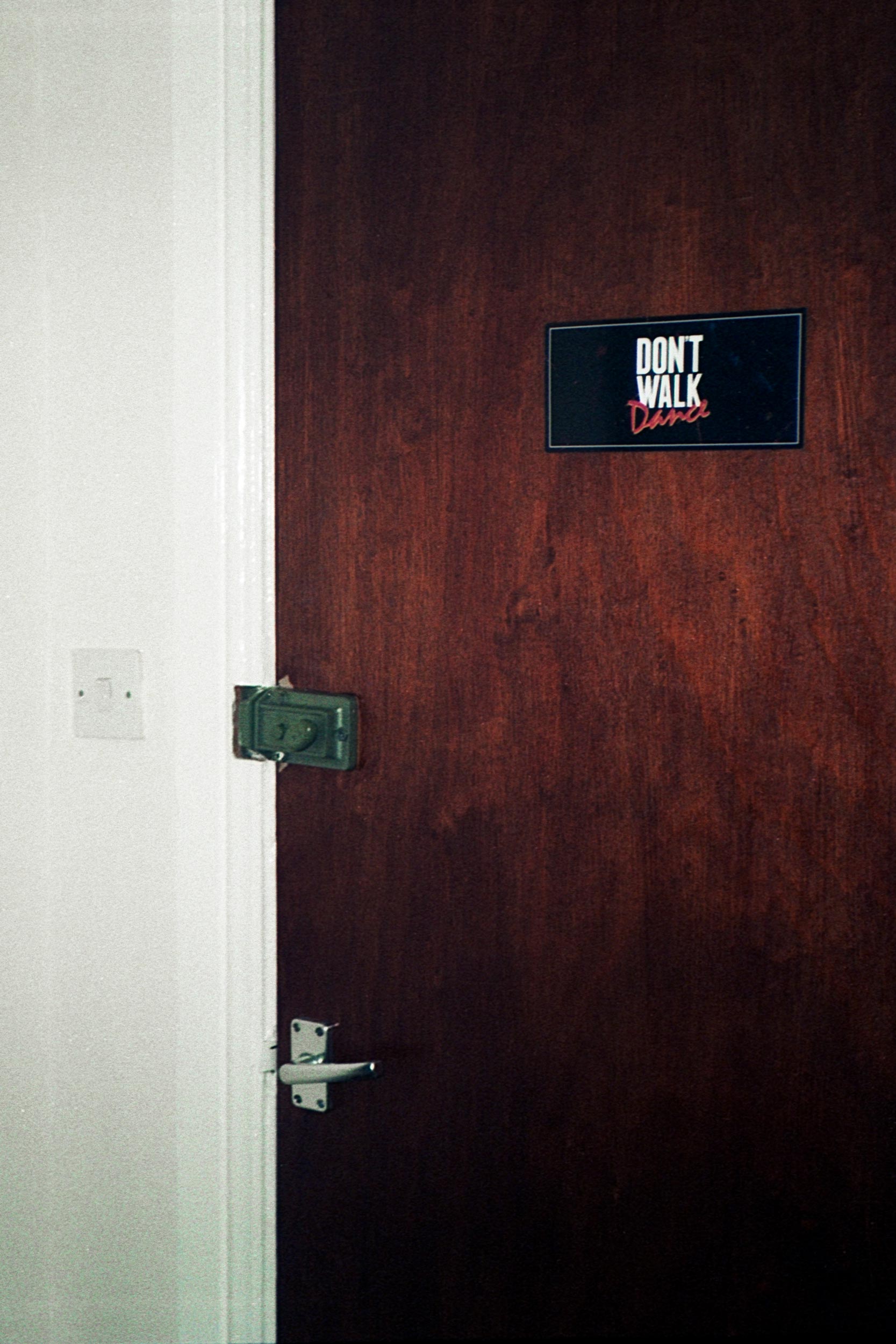 Eine Holztür mit einem Schild Don't walk Dance