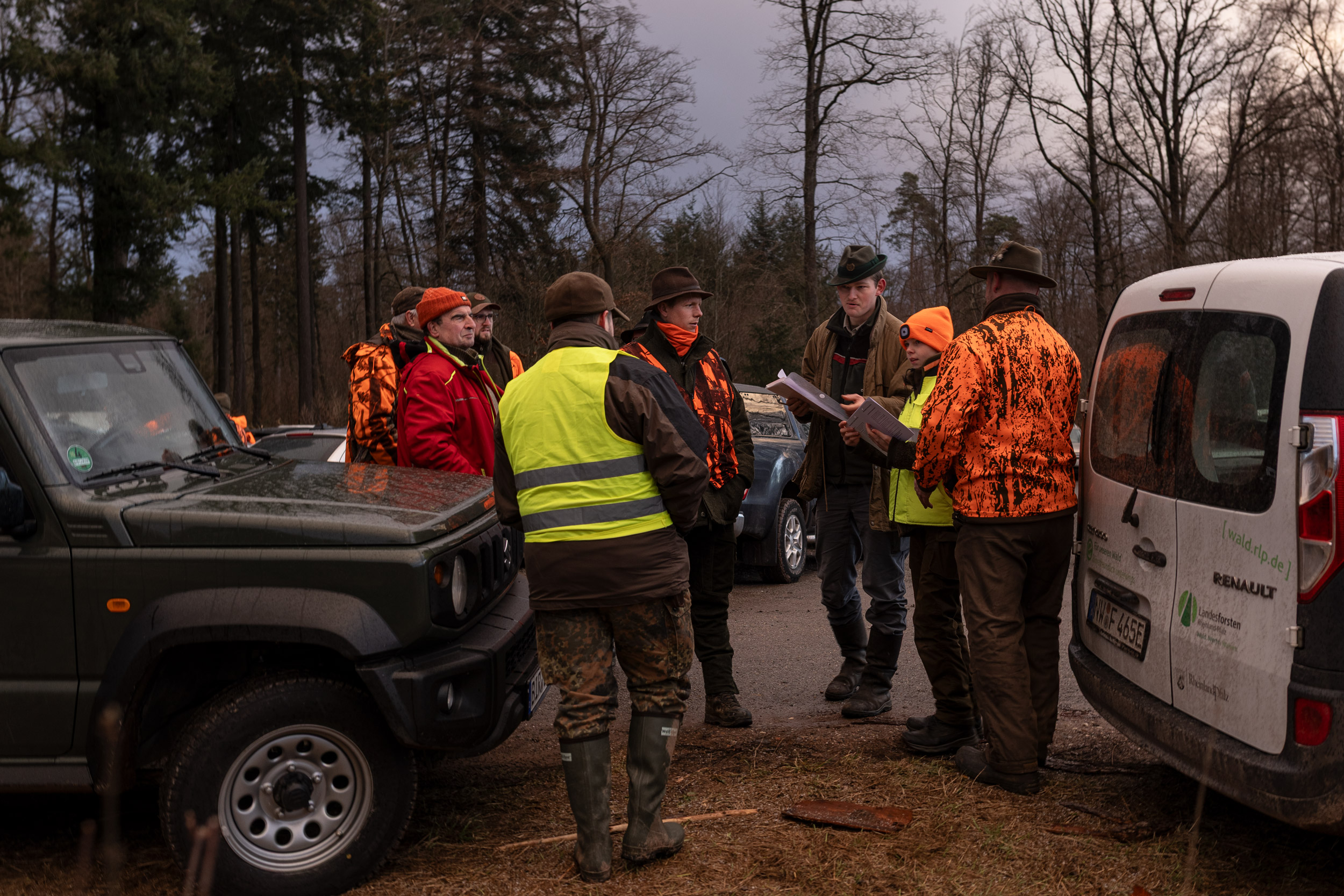 Förster Nico Grub instruiert seine Untergruppe zu Beginn der Drückjagd. Die Regulierung von Wildbeständen durch die Jagd verhindert Wildverbiss, der wiederum die wichtige Waldverjüngung gefährdet. Die Drückjagd gilt als besonders kontroverse Form der Jagd, da sie einerseits die Tiere des Waldes unter Stress setzt und Schützen extrem gefährdet. Andererseits wird auf effektive Weise in kürzester Zeit viel Wild entfernt. Durch die Wiederansiedelung von Luchs und Wolf im Pfälzerwald könnte ein ökologisches Gleichgewicht auf natürlichere Weise wiederhergestellt werden. (Forstamt Johanniskreuz)